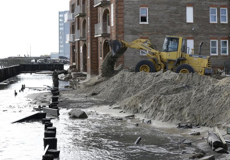 A worker uses a backhoe to move sand near a boardwalk that was destroyed by superstorm Sandy in Atlantic City, N.J., on Wednesday. (Patrick Semansky/AP)