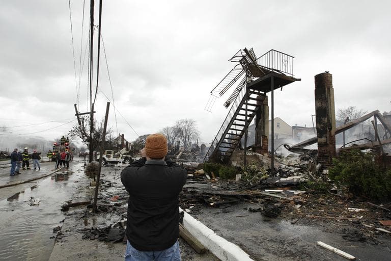 A man photographs damage caused by a fire in the Belle Harbor neighborhood in the New York City borough of Queens on Tuesday. (Frank Franklin II/AP)