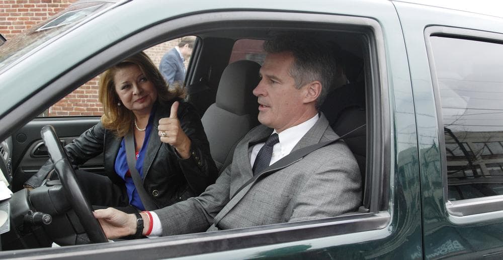 U.S. Sen. Scott Brown drives his truck as his wife Gail Huff gestures to supporters after a campaign stop in Watertown Oct. 24. (Charles Krupa/AP)