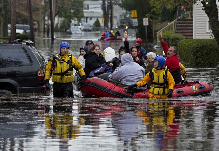People, some waving to those on dry ground, are rescued by boat in Little Ferry, N.J. Tuesday, Oct. 30, 2012 in the wake of superstorm Sandy. Sandy, the storm that made landfall Monday, caused multiple fatalities, halted mass transit and cut power to more than 6 million homes and businesses. (AP)