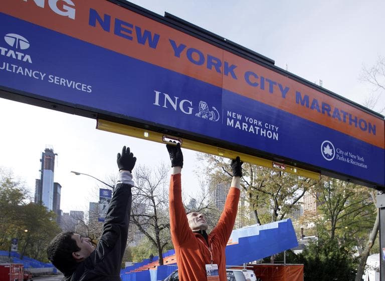Workers assemble the finish line for the New York City Marathon in New York's Central Park on Thursday. The crane atop a high rise that collapsed during Superstorm Sandy is visible at background left. (AP Photo/Richard Drew)