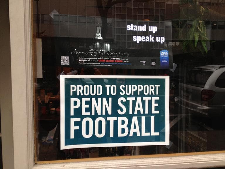 A common juxtaposition of signs in State College storefronts, one pledging support for the football team, the other for victims of sexual abuse. (Adam Ragusea/Georgia Public Broadcasting)