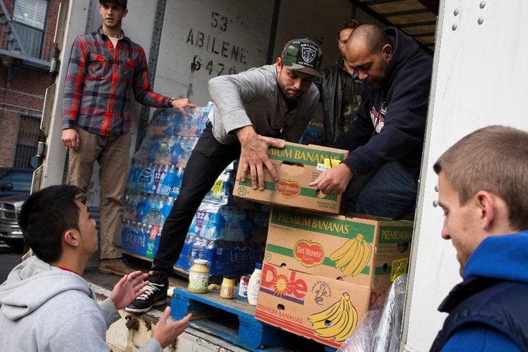 Volunteers help unload food from a truck on Friday, for distribution to the residents of the Lower East Side in Manhattan, New York. (John Minchillo/AP)