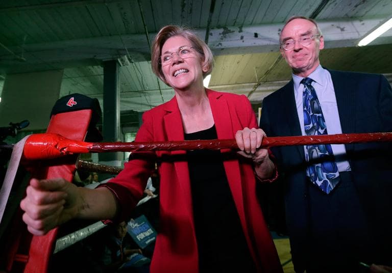 Elizabeth Warren, with her husband Bruce Mann, shakes hands from a boxing ring during a campaign rally at Ramalho's West End Gym in Lowell on Friday. (Elise Amendola/AP)