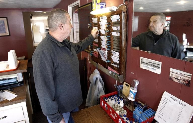 In this Nov. 9, 2011, photo, owner Russ Caswell reaches for a room key behind the front desk of the Motel Caswell in Tewksbury. (Winslow Townson/AP)