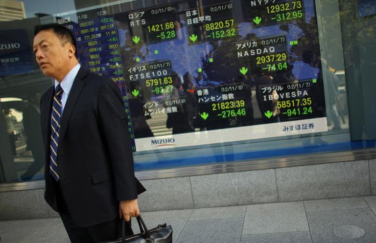 A man stands outside a securities firm in Tokyo on Thursday. Asian stock markets tumbled Thursday after a ratings agency threatened to downgrade the U.S. if a solution to the so-called fiscal cliff isn't negotiated among lawmakers and newly re-elected President Barack Obama. (Junji Kurokawa/AP)
