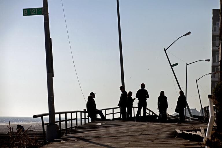 People gather on the buckled boardwalk of the Rockaway Park neighborhood of the borough of Queens, New York. (AP Photo/Craig Ruttle)