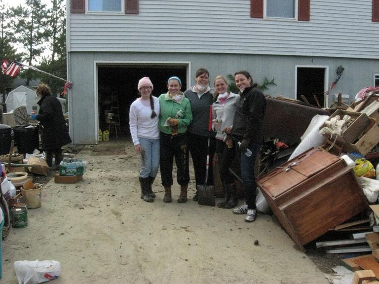 A group of volunteers from Saint Anselm College in New Hampshire pause for a photo outside a damaged home in Holgate, N.J. (Chris Ballman/Here & Now)