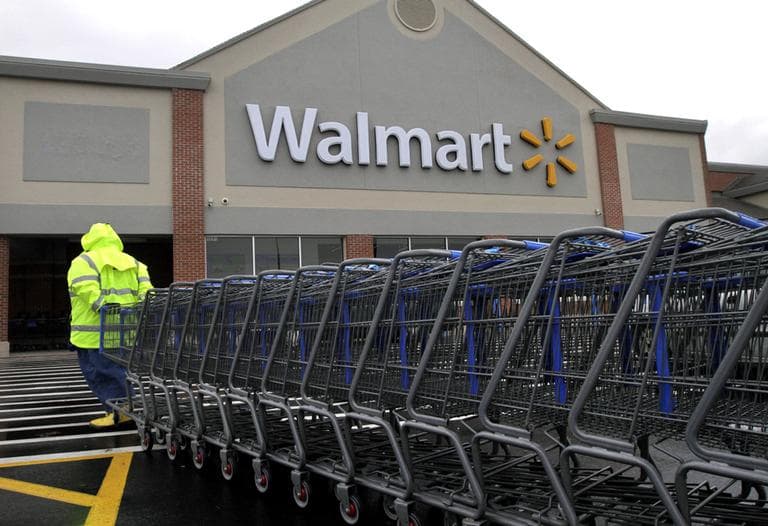 A worker pulls a line of shopping carts toward a Walmart store in North Kingstown, R.I. in November 2012. (Steven Senne/AP)