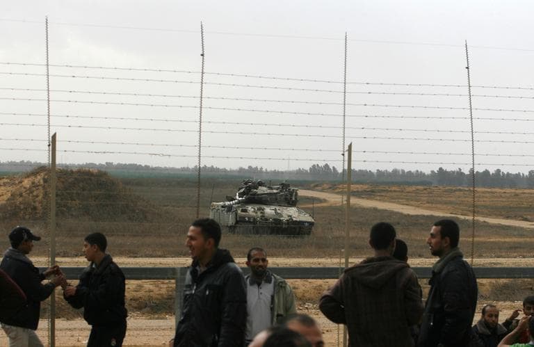 An Israeli army tank keeps position near a security fence on the Gaza border with Israel, as Palestinians approach the fence east of Khan Younis, southern Gaza Strip, on Friday. (Eyad Baba/AP)