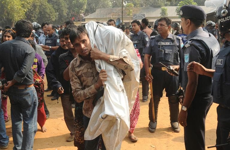A Bangladeshi man carries the body of his relative killed in a fire at a garment factory outside Dhaka, Bangladesh. (Hasan Raza/AP)