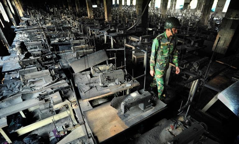 A Bangladeshi police officer walks between rows of burnt sewing machines in a garment factory outside Dhaka, Bangladesh on Sunday. At least 112 people were killed in a late Saturday night fire that raced through the multi-story factory. (Khurshed Rinku/AP)