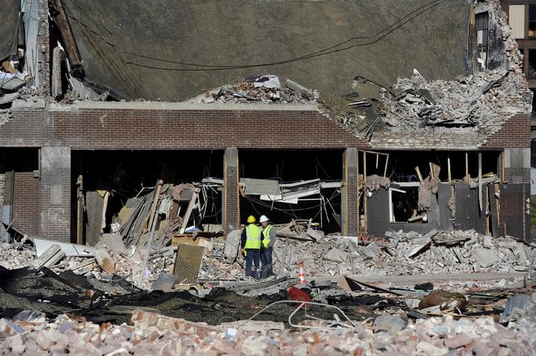 Inspectors stand in debris on Saturday at the site of a gas explosion that leveled a strip club in Springfield, Mass., on Friday evening. (Jessica Hill/AP)
