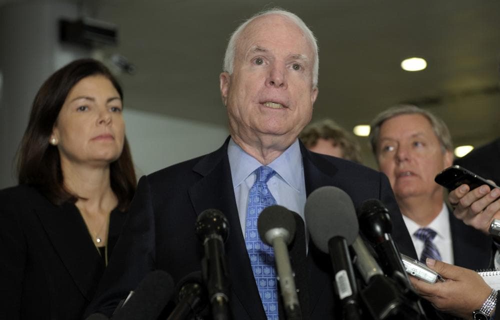 Sen. John McCain, ranking Republican on the Senate Armed Services Committee, flanked by fellow committee members, Sen. Kelly Ayotte,  left, and Sen. Lindsey Graham, right, speaks after a meeting with U.N. Ambassador Susan Rice. (Susan Walsh/AP)