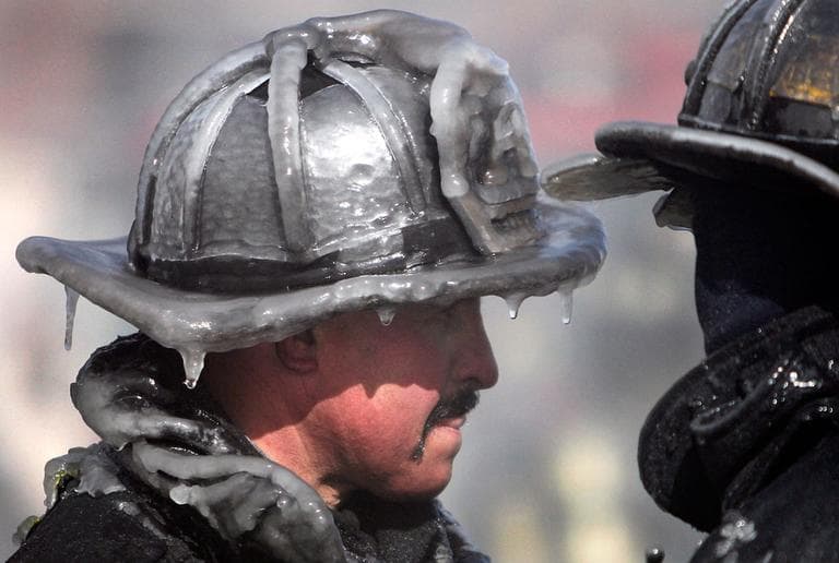 A firefighter's helmet is caked in ice at the scene of a four-alarm fire in Boston, Sunday, Feb. 12, 2012. Freezing temperatures and high wind hampered efforts to fight the blaze. (AP Photo/Michael Dwyer)