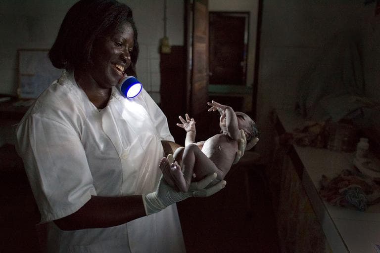 Chief midwife Maria Antoneta Cabral Barbosa holds a newborn baby boy she has just delivered by flashlight, at the regional hospital in Gabu, Guinea-Bissau, May 23, 2012. In Guinea-Bissau, one of the deadliest places in the world to give birth, a woman has a 1 in 19 chance of maternal death, compared to about 1 in 2,100 in the United States. (AP Photo/Rebecca Blackwell)