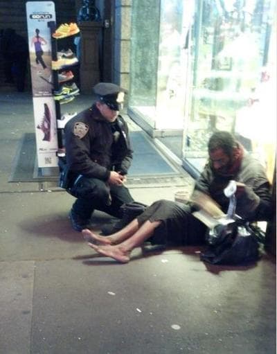 Officer Larry DePrimo gives new boots to a barefoot man. (NYPD Facebook page)