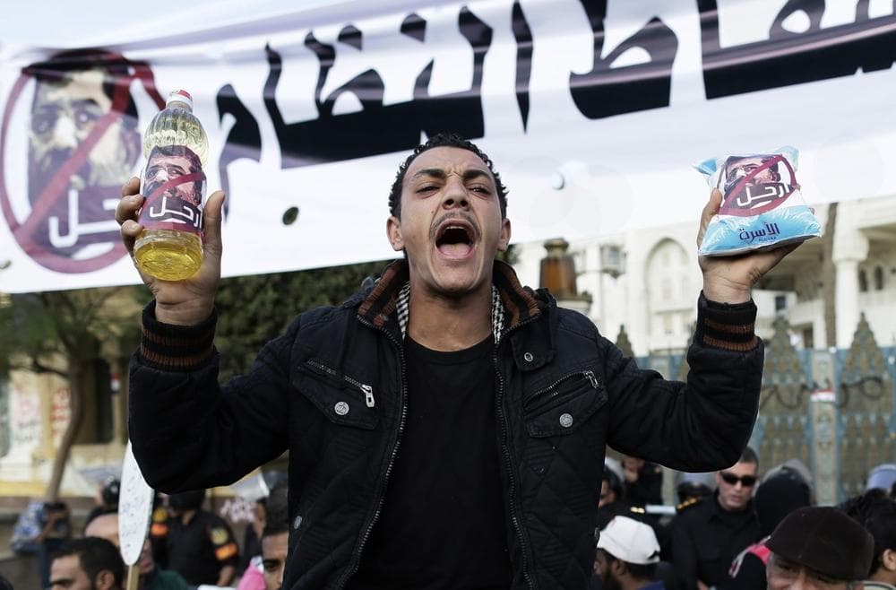 An Egyptian protester holds up a battle of oil and a bag of sugar as he chants anti-Muslim Brotherhood and Egyptian President Mohammed Morsi slogans outside the presidential palace in Cairo, Egypt, Saturday, Dec. 8, 2012. (Hassan Ammar/AP)