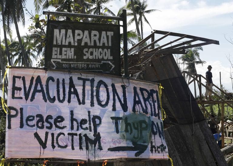 A typhoon victim rebuilds his damaged house near a sign asking for aid for victims of Typhoon Bopha at Maparat township, Compostela Valley in southern Philippines Saturday Dec. 8, 2012. (Bullit Marquez/AP)