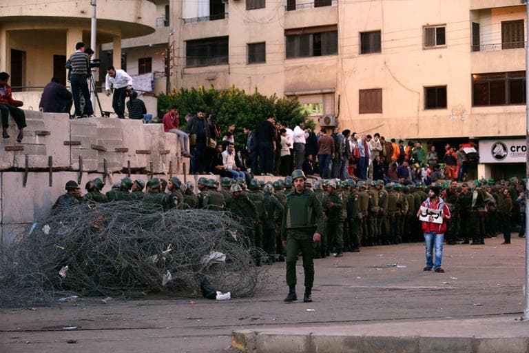 Egyptian army soldiers stand guard as protesters stand on top of cement blocks near the presidential palace in Cairo, Egypt, Sunday, Dec. 9, 2012. (Hassan Ammar/AP)
