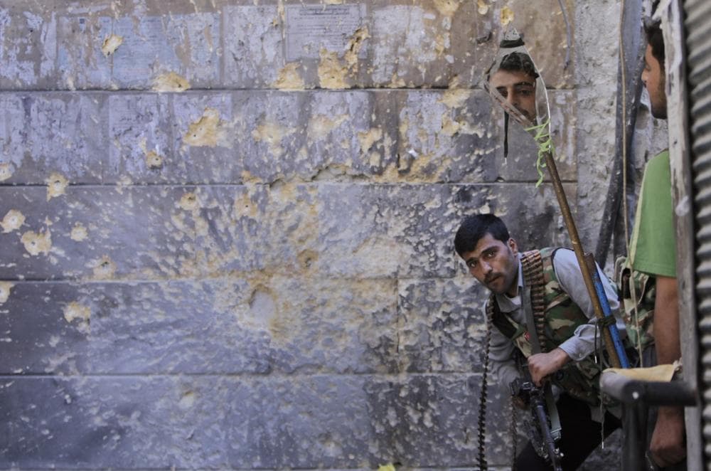 A Free Syrian Army soldier, right, looks through a mirror which helps him see Syrian troops from the other side, as he takes his position with his comrade during fighting, at the old city of Aleppo city, Syria, Monday Sept. 24, 2012. (AP Photo/Hussein Malla)