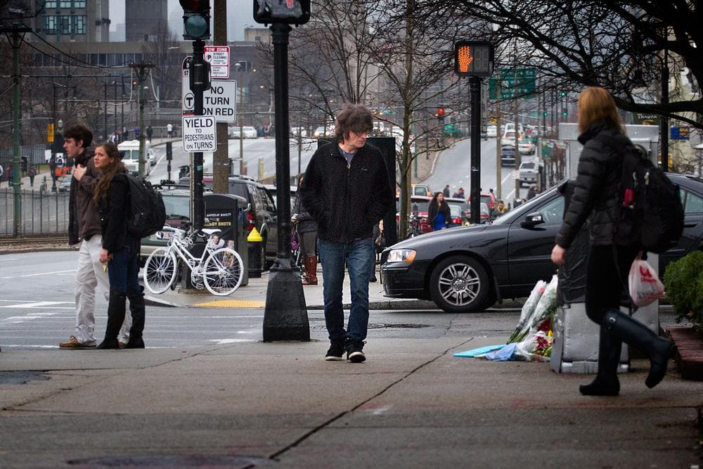 A man looks at the Memorial created for Christopher Weigl on Commonwealth Avenue. The ghost bike sits locked up across St. Paul Street. (Jesse Costa/WBUR)