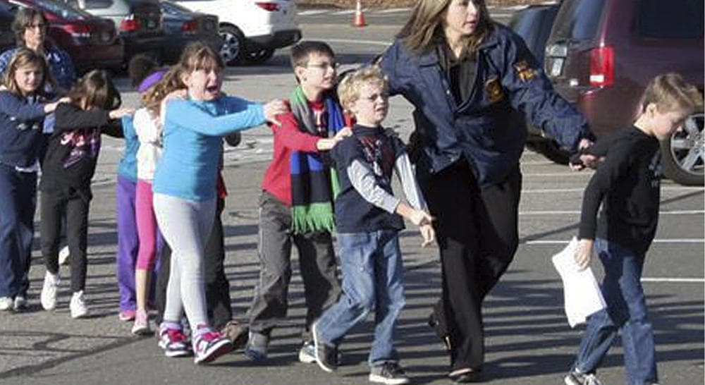 In this photo Connecticut State Police lead children from the Sandy Hook Elementary School in Newtown, Conn., following a shooting there Friday, Dec. 14, 2012.  (Shannon Hicks/Newtown Bee, AP)  