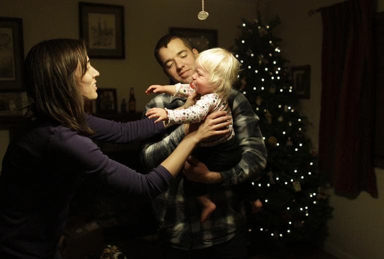 A newly-decorated Christmas tree lit behind him, U.S. Army's 1st Lt. Aaron Dunn hands his baby Emma to his wife Leanne, in their living room, a week following Dunn's return from a tour of duty in Afghanistan, in Fountain, Colo., Saturday Dec. 8, 2012.  (AP/Brennan Linsley)