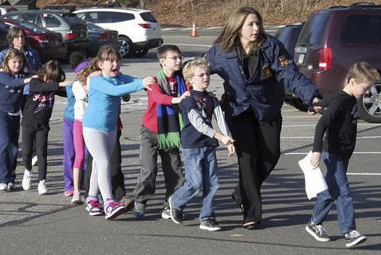 In this photo provided by the Newtown Bee, Connecticut State Police lead children from the Sandy Hook Elementary School in Newtown, Conn., following a mass shooting Friday. (Shannon Hicks/AP/Newtown Bee)