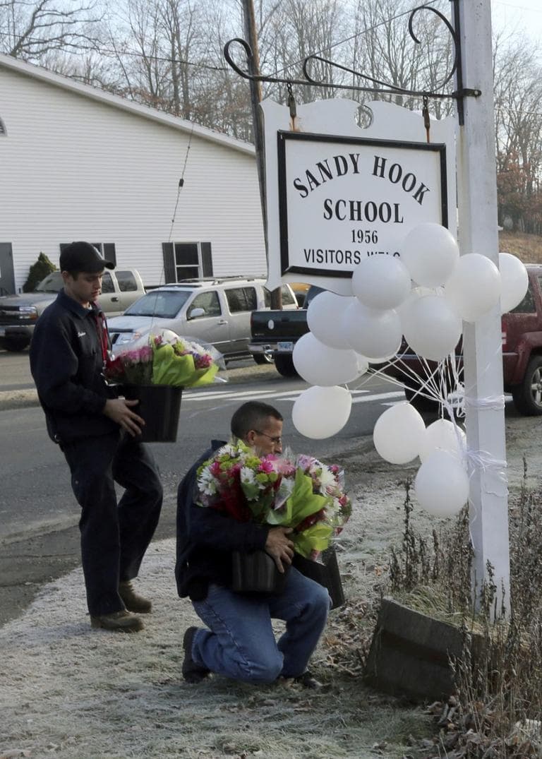 Volunteer firefighters place flowers at a makeshift memorial at a sign for the Sandy Hook Elementary school Saturday, Dec. 15, 2012 in Newtown, Conn. (Mary Altaffer/AP)