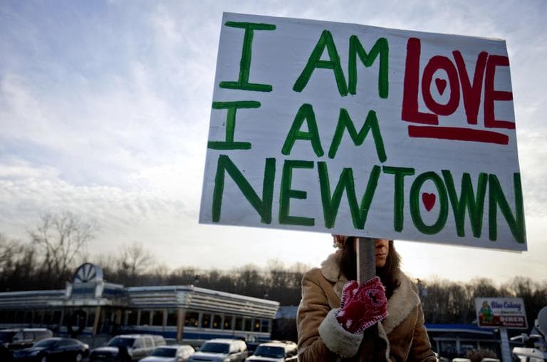 A Newtown, Conn., resident, who declined to give her name, holds a sign for passing motorists up the road from the Sandy Hook Elementary School, Saturday, Dec. 15, 2012. (David Goldman/AP)