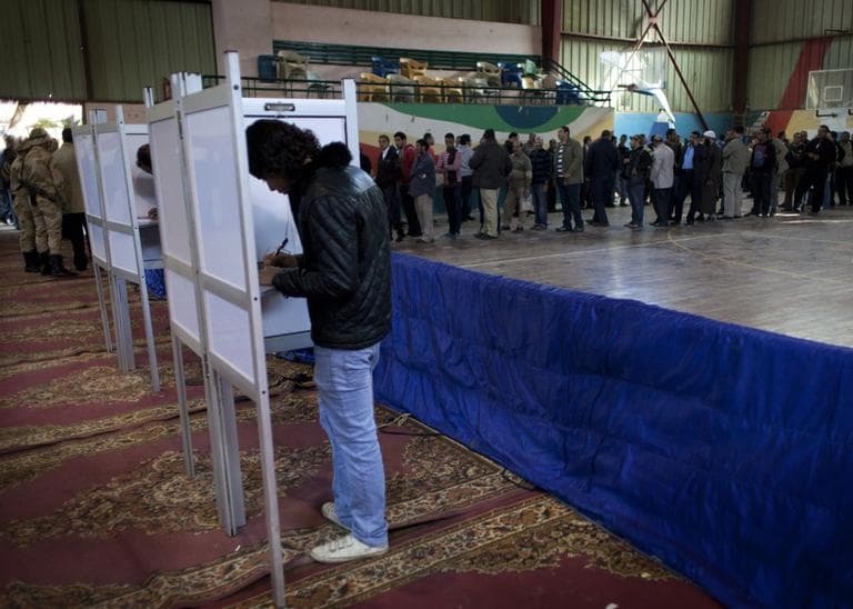 Two Egyptian men vote while other voters wait in line at gymnasium hall used as a polling station during the second round of a referendum on a disputed constitution in Giza, Egypt, Saturday, Dec. 22, 2012. (Nasser Nasser/AP)