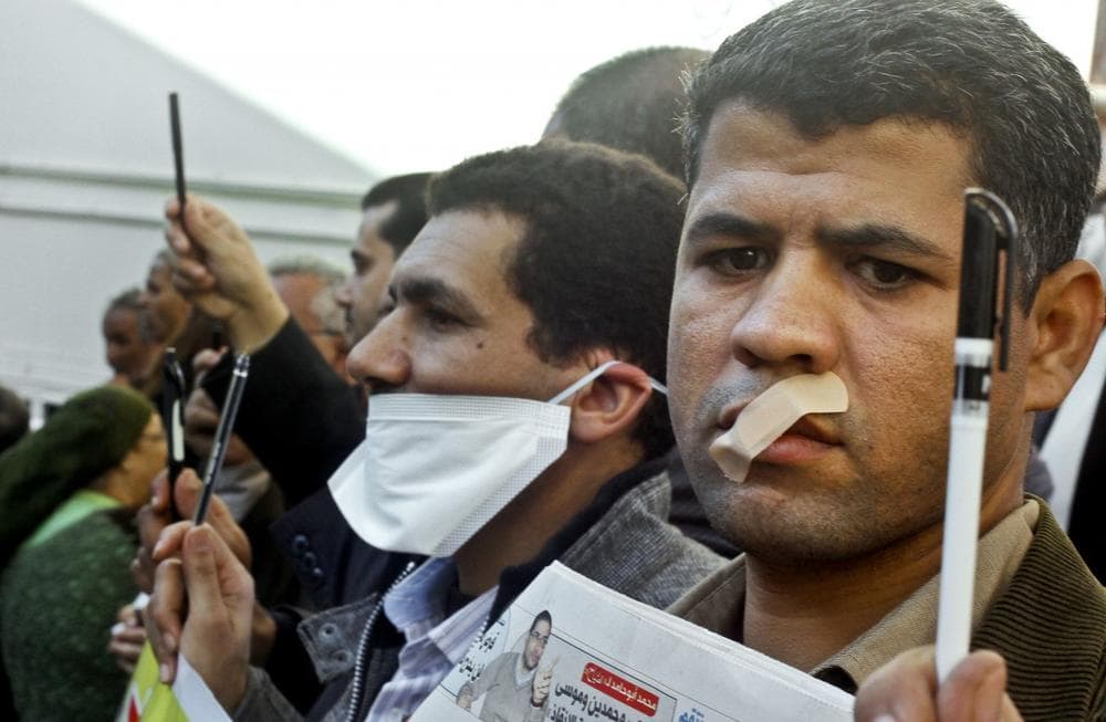 Egyptian journalists tape their mouths and raise their pens during a demonstration against the draft constitution in Cairo, Egypt, Sunday, Dec. 23, 2012. Egypt's opposition called Sunday for an investigation into allegations of vote fraud in the referendum on a deeply divisive Islamist-backed constitution after the Muslim Brotherhood, the main group backing the charter, claimed it passed with a 64 percent &quot;yes&quot; vote. (Amr Nabi/AP) 
