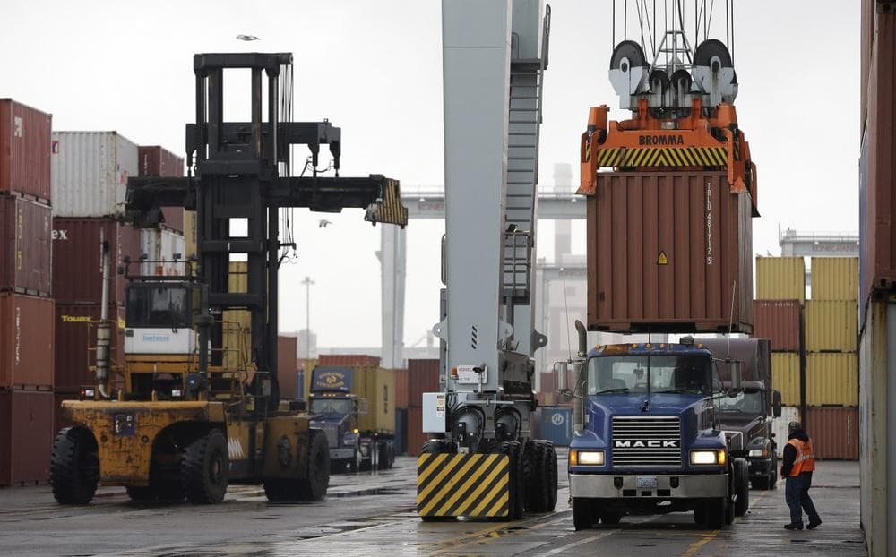 In this photo taken Tuesday, Dec. 18, 2012, a truck driver watches as a freight container, right, is lowered onto a tractor trailer truck by a container crane at the Port of Boston, in Boston. The crane and a reach stacker, left, are operated by longshoremen at the port. (Steven Senne/AP)