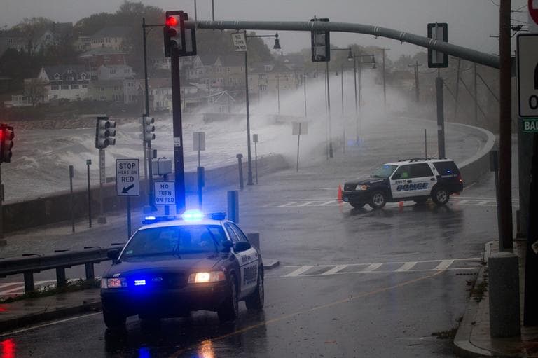 Revere Police block Winthrop Parkway as waves crash against the sea wall on Monday. (Jesse Costa/WBUR)