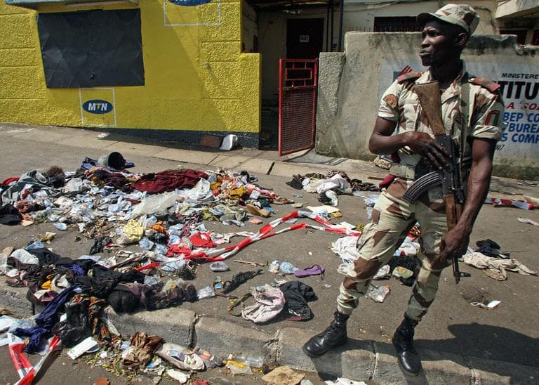 An Ivory Coast soldier stands next to the belongings of people involved in a deadly stampede in Abidjan, Ivory Coast, Tuesday, Jan. 1 2013. (Emanuel Ekra/AP)