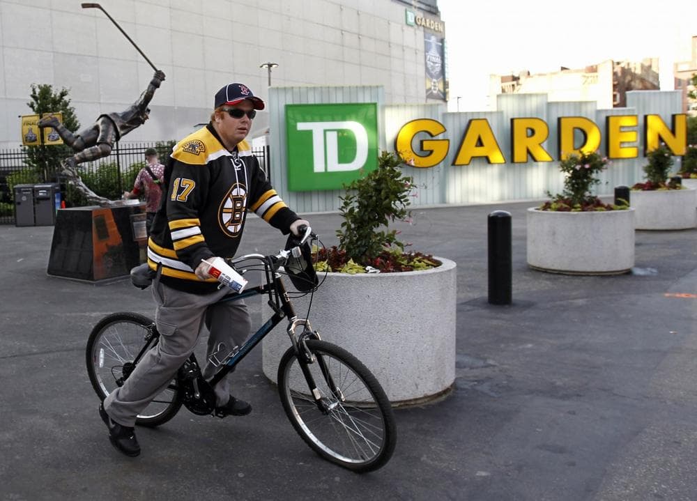Bruins fan Paul Cuscuma, of Medford, rides his bike in front of the Bobby Orr Statue outside the TD Garden in Boston Sunday, June 5, 2011. (Winslow Townson/AP)