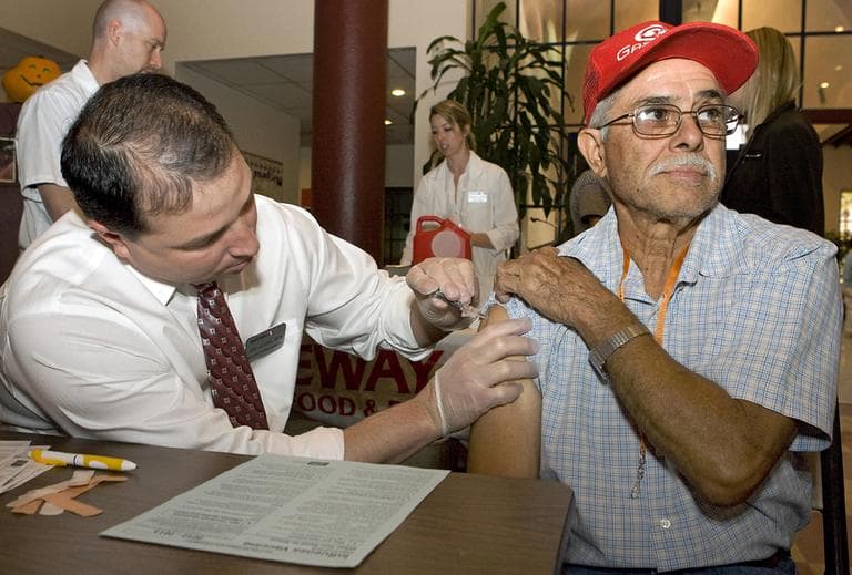 Jesus Ortiz, right, gets his flu shot from Joe Leyba, left, during a flu shot clinic at the Armory Park Senior Center in Tucson, Ariz., in October 2012. (John Miller/AP/NCOA)