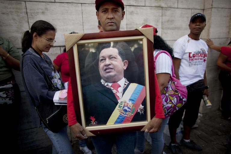 A supporter of Venezuela's President Hugo Chavez poses for a portrait as he holds a photograph of Chavez outside the National Assembly in Caracas, Venezuela on Saturday. (Ariana Cubillos/AP)