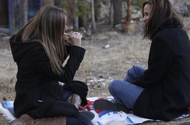 In this November 2012 photo, two women smoke marijuana together, behind a home in the woods near the small Rocky Mountain town of Nederland, Colo. (Brennan Linsley/AP)