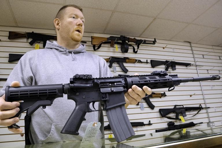 John Jackson, co-owner of Capitol City Arms Supply, holds an AR-15 rifle for sale at his business in Springfield, Ill. on Wednesday. (Seth Perlman/AP)
