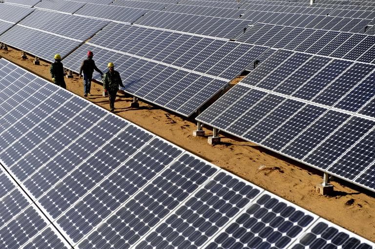 In this November 2010 photo released by China's Xinhua News Agency, workers check on solar panels in Yulin, northwest China's Shaanxi Province. (Liu Xiao/Xinhua/AP)