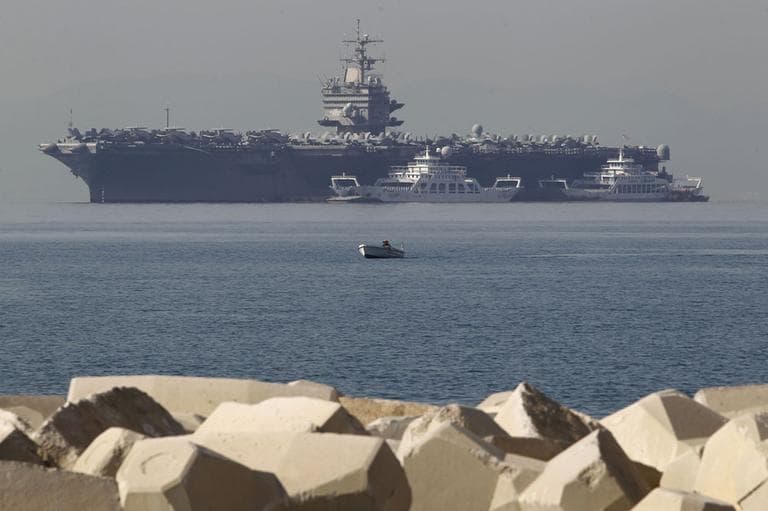 A small boat passes in front of the aircraft carrier USS Enterprise anchored of the coast of Faliro, near Athens. (AP)