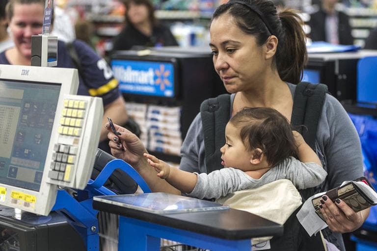 Consumer Eva Cevallos with her eleven-month daughter, Quinn, pays with a credit card at Walmart. (AP)