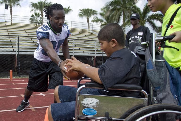 Seattle Seahawks football player Kennard Cox hands the football off to Juan Herrera during the fifth annual 12th Man Football Cheer Camp in Miami Lakes, Fla., Saturday, Feb. 25, 2012. The 12th Man Football Cheer Camp was created by Miami Dade police officer Allen Lowy to give those with special needs or disabilities the opportunity to be a part of organized football. (AP)