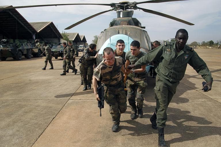 Malian soldiers helped by French troops, move a broken helicopter out a hangar to make room for more incoming troops at Bamako's airport Tuesday Jan. 15. 2013. (AP)