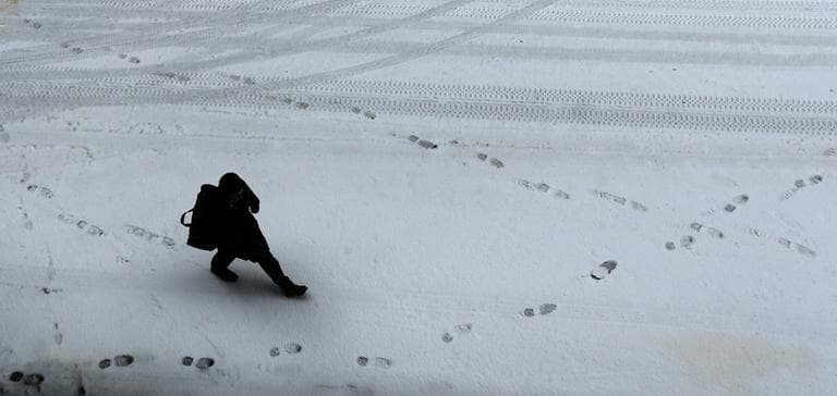  man makes fresh tracks in the snow as he walks through the Financial District of Boston on Friday. (Charles Krupa/AP)