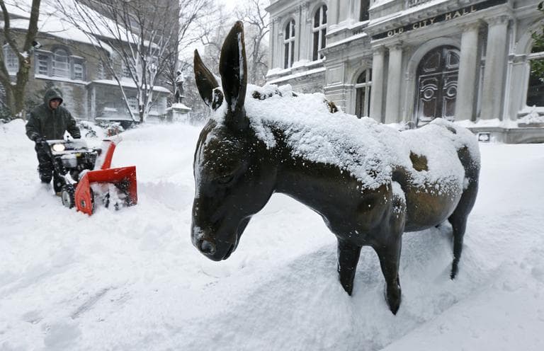 A worker clears as he passes a snow-covered donkey statue outside Old City Hall in Boston on Saturday. (Charles Krupa/AP)