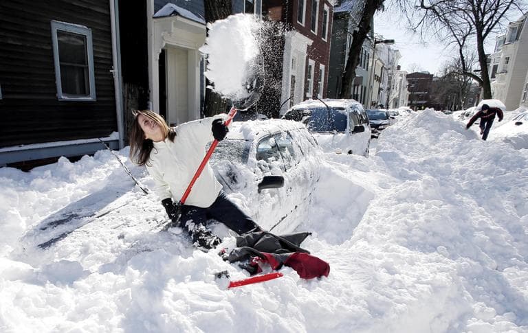 Leslie McVicker sits on the hood of her car to shovel out on an unplowed street in Boston, Sunday, Feb. 10, 2013. (Winslow Townson/AP)