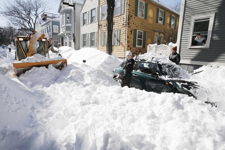 A City of Boston snow machine operator informs a couple that they will need to shovel their car out all over again after he clears the snow from their unplowed street in Boston Sunday, Feb. 10, 2013. (Winslow Townson/AP)